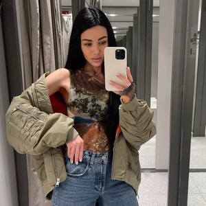 Selfie miroir avec veste aviateur vert herbe, haut en mesh imprimé et jean bleu vintage