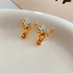 Macro detail of 18k gold plated butterfly clip-on earring with blue resin wings