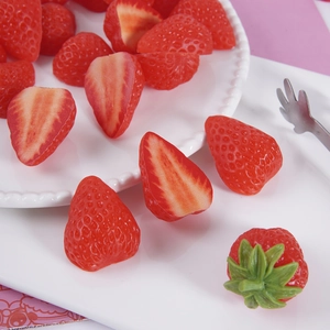 Realistic artificial strawberry halves and whole fruits on white plate for DIY crafts