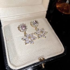 Detail of pink flower drop earrings with crystal zircons on a white jewelry cushion