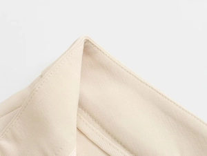 Macro detail of the neat stitching and beige woven fabric on the tube top and trousers