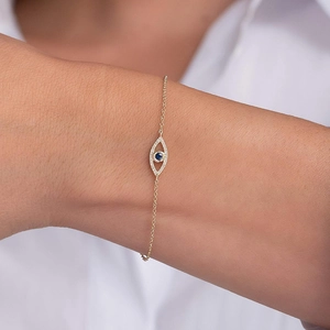 Detailed view of gold evil eye bracelet with blue stone and white zircons on wrist