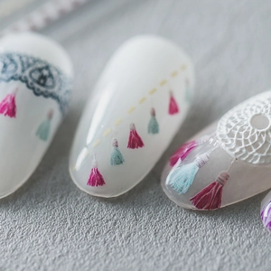 Bohemian style nail stickers with pink tassels and white lace on matte gray background