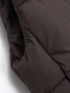 Detail view of coffee brown puffer vest featuring windproof fabric and stitching on pocket