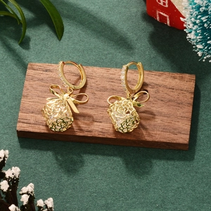 Detailed close-up of golden hollow gift box earrings with bows and sparkling crystals