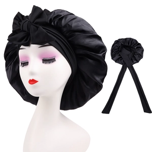 Detail of black satin sleep cap with large bow design on a white mannequin head