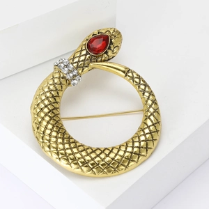 Elegant gold snake brooch with red gemstone eye and white rhinestones on white background