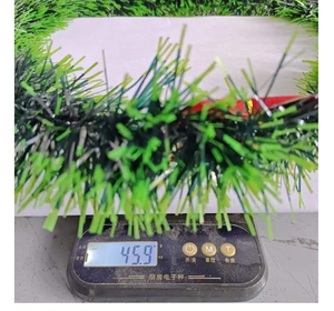 Close-up of a 45.9g lightweight green Christmas wreath garland being weighed on a scale