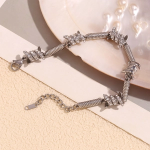 Macro detail of silver barbed wire bracelet with pave crystals on sandy texture