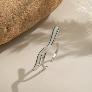 Macro shot of a minimalist silver wavy ring on a matte surface with natural stone decor