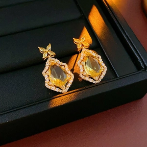 Detailed view of pear-cut yellow crystal earrings with butterfly design in gold setting