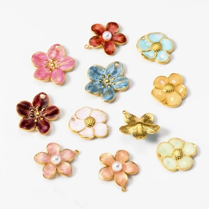 Flat lay of colorful enamel flower charms with pearls for DIY jewelry making