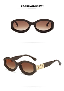 Detailed view of brown oval sunglasses with golden hollow-out metal hinges and gradient lenses