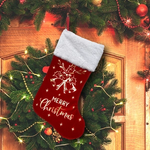 Close-up of red velvet Christmas stocking with white faux fur and golden bell prints
