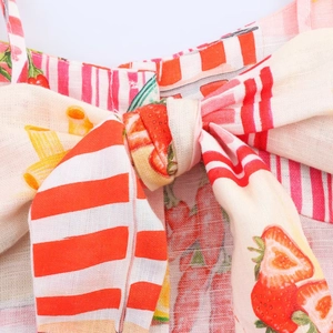 Détail macro d'un nœud en coton et lin avec imprimé fraise et rayures rouges sur robe