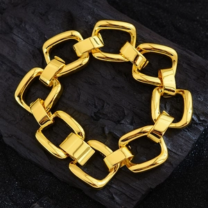 Fashionable chunky gold geometric chain link bracelet on a textured black wood surface