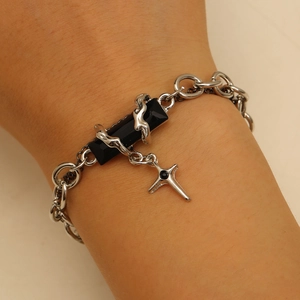Detail of silver chain bracelet with rectangular black stone and cross charm on wrist