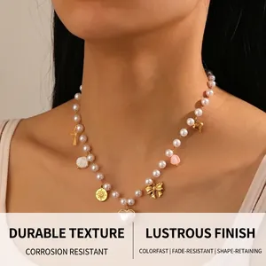 Detail of faux pearl necklace with gold heart and star charms on a model neck
