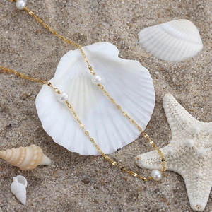 Elegant 925 sterling silver gold necklace with fresh water pearls on shell and beach sand