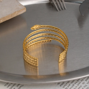 Macro shot of 18K gold plated snake-shaped cuff with intricate scale texture on metal tray
