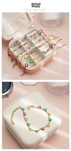Detail of colorful enamel evil eye bracelets in gold plating on a pink display box