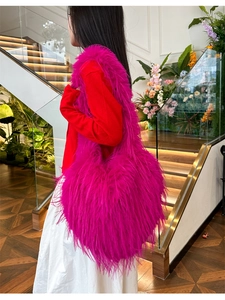 Hot pink fluffy heart faux fur shoulder bag worn by model in a stylish indoor setting