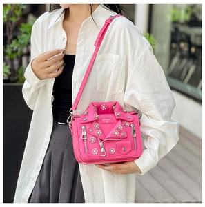 Detail of rose pink jacket-shaped crossbody bag with floral metal studs and zipper accents