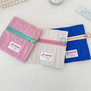 Close-up of pleated cosmetic bags with contrast zippers and Sazakka logo label