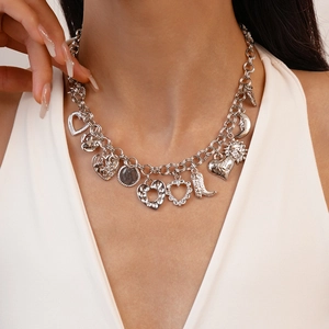 Detail of silver chunky necklace with heart, moon, and cowboy boot charms on a white top