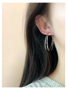 Nahaufnahme von doppellagigen silbernen Creolen am Modell im minimalistischen Stil