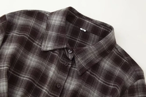 Detailed view of dark plaid flannel shirt collar and buttons with size M label