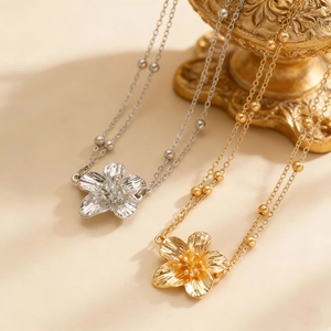 Gedetailleerde macro van de bohemien frangipani bloementailleketting in goud en zilver
