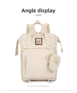 Front view of cream multifunctional diaper backpack with embroidered patch and cupcake charm