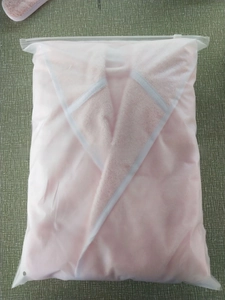 Detailed view of a soft pink plush bathrobe neatly folded inside a frosted zipper bag