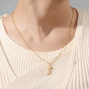 Elegant gold stainless steel floral pendant necklace worn over a white knit sweater