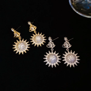Close-up of sparkling planet and sun earrings with pave set zircons in gold and silver
