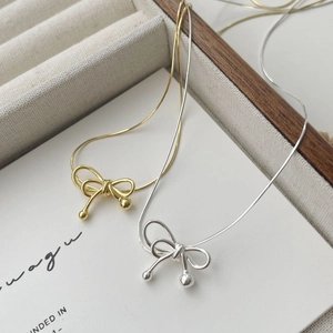 Elegant S925 silver bow pendant necklace in gold and silver finishes on display
