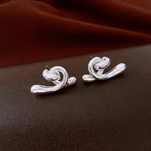 Close-up of silver irregular twisted knot stud earrings on premium leather texture