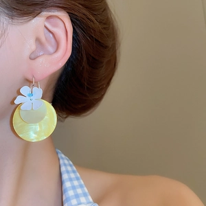 Detail view of yellow floral drop earrings on model for a fresh summer vacation style
