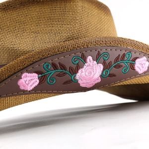 Close-up of pink rose embroidery and green vines on brown leather cowboy hat band