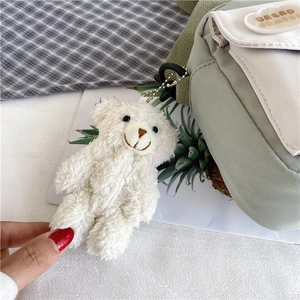 Gros plan d'un porte-clés ours en peluche blanc sur un sac en toile vert clair