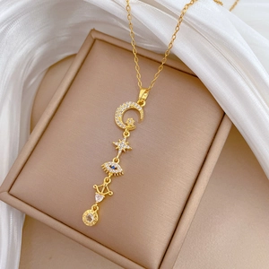 Close-up of tassel necklace featuring crystal moon, star, and evil eye pendants