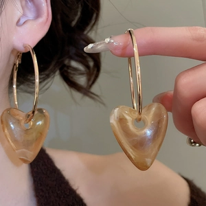 Detail of gold hoop earrings featuring amber marbled acrylic heart pendants for women