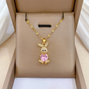 Dettaglio collana con coniglio, pietra a cuore rosa e piccoli cristalli su seta bianca