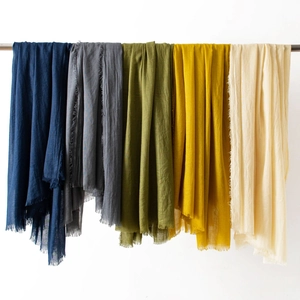 Detail of five linen blend scarves in various colors with fringed edges on a metal rod