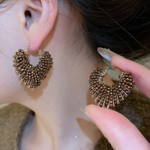 Close-up of heart-shaped crystal beaded hoop earrings with bronze metallic finish