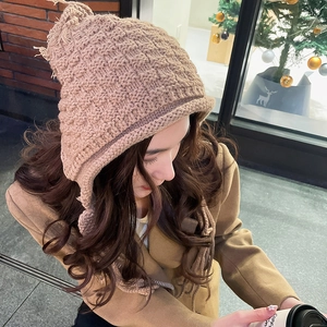 Detailed view of the chunky knit earmuff hat with tassel fringe in light nude pink