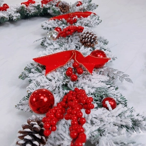 Close-up of Christmas garland with snow-flocked needles, red berries, and pine cones