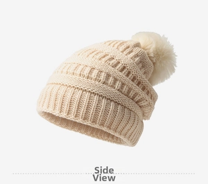 Détail du bonnet d'hiver en grosse maille avec pompon en fausse fourrure blanc crème