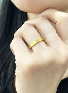 Close-up of a matte 18k gold plated stainless steel ring on a model's finger